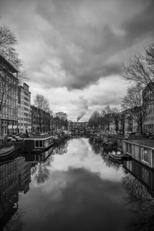 Canal in Amsterdam with dramatic stormy clouds, in the background it seems the factory chimney is producing the cloudsのeditorial素材