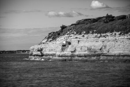 View from the Gironde estuary with the limestone cliff of the village of Meschers sur Gironde and its troglodytic houses and traditionnal typical wooden fisherman cabins, Charente maritime, Franceの写真素材
