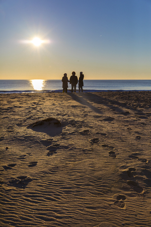 Silhouette of people walking on the beach by romantic winter sunset, L'aiguillon sur Mer, Vendee, Franceの写真素材