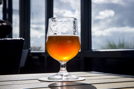 Fresh glass of light amber beer on a table in a pub terraceの写真素材