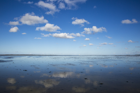 Maritime landscape with reflection of clouds in low tide water, Waddenzee, Friesland, The Netherlandsの写真素材