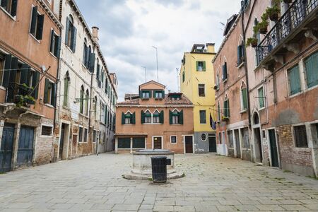 view on a Venetian square or piazza with traditional historic buildings and a wellの写真素材
