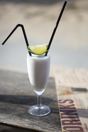 Cocktail glass with two straws and with beach landscape backgroundの写真素材