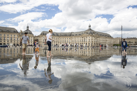 BORDEAUX, FRANCE â April 25, 2015: le Miroir dâEau, water mirror near Place de la Bourse designed by landscape artist Michel Corajoud, full of people having fun one of 1st warm spring day of the yearのeditorial素材