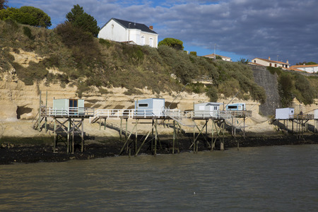 View from the Gironde estuary with the limestone cliff of the village of Meschers sur Gironde and its troglodytic houses and traditionnal typical wooden fisherman cabin, Charente maritime, Franceの写真素材