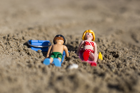 Amsterdam, the Nertherlands. April 12 3, 2015. A man and a woman sun tanning on the sand. Playmobil toy line exist since 1975 and is produced by the German company Brandtaetter.のeditorial素材