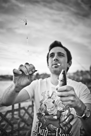ISTANBUL - MAY 2013: Unidentified fisher holding his catch on Galata bridge in Istanbul, Turkey on May 19, 2013.The Galata Bridge is a bridge that spans the Golden Hornのeditorial素材