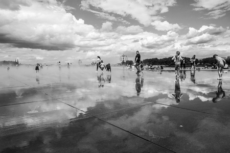 BORDEAUX, FRANCE â April 25, 2015: âle miroir dâeauâ water mirror near Place de la Bourse designed by landscape artist Michel Corajoud, full of people having fun one of 1st warm spring day of the yearのeditorial素材