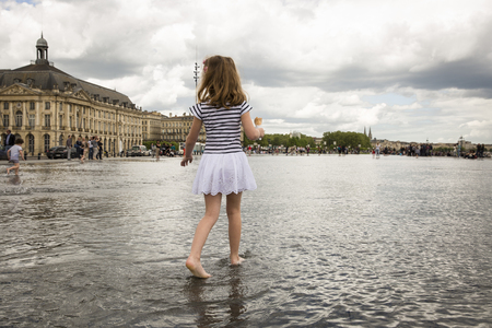 BORDEAUX, FRANCE - April 25, 2015: le Miroir d'Eau, water mirror near Place de la Bourse designed by landscape artist Michel Corajoud, full of people having fun one of 1st warm spring day of the yearのeditorial素材