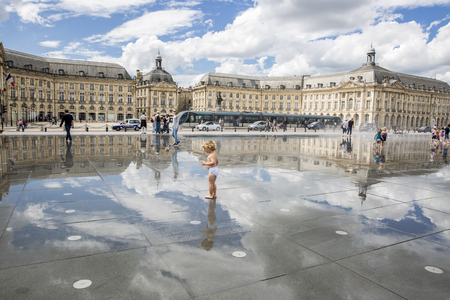 BORDEAUX, FRANCE- April 25, 2015: le Miroir d'Eau, water mirror near Place de la Bourse designed by landscape artist Michel Corajoud, full of people having fun one of 1st warm spring day of the yearのeditorial素材
