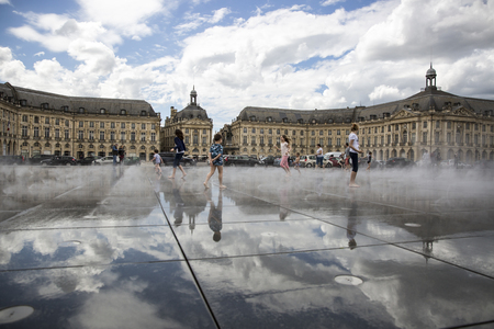 BORDEAUX, FRANCE - April 25, 2015: le miroir d'Eau, water mirror near Place de la Bourse designed by landscape artist Michel Corajoud, full of people having fun one of 1st warm spring day of the yearのeditorial素材