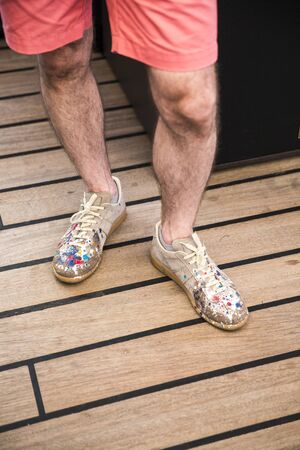 Man with shoes fashionably covered with colorful paint drops