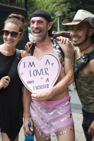 Amsterdam, the Netherlands - July 23, 2016: man lightly dress in pink holding a sign saying âIâm a lover, not a fighterâ, during Pink Saturday celebration in Vondelpark for 2016 Gay Euro Prideのeditorial素材