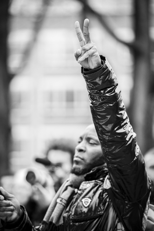 Amsterdam, The Netherlands - February 6,2016: public multi-cultural demonstration organized to protest against racism and islamophobia named "Refugees welcome, racism not!" A black man is raising his fistのeditorial素材