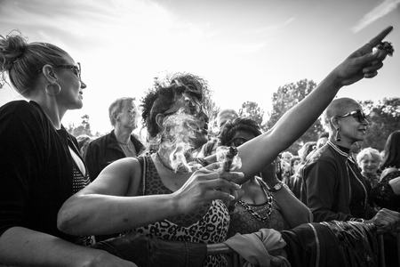 Amsterdam, The Netherlands - July, 3 2016: woman smoking a cigar during concert of Cuban band Elito Reve y su Charangon at Amsterdam Roots Open Air, free public cultural festival held in Oosterparkのeditorial素材