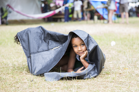Amsterdam, The Netherlands - July, 5 2015: young black boy hiding from the rain under a cover during Amsterdam Roots Open Air, a cultural festival held in Park Frankendael on 05/07/2015のeditorial素材