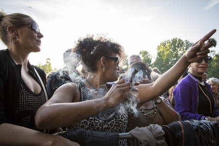 Amsterdam, The Netherlands - July, 3 2016: woman smoking a cigar during concert of Cuban band Elito Reve y su Charangon at Amsterdam Roots Open Air, free public cultural festival held in Oosterparkのeditorial素材