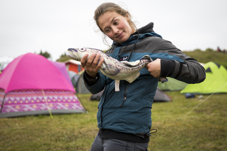 Traena, Norway - July 10 2015: funny young woman fooling around with fake fish, at Traenafestival, music festival taking place on the small island of Traenaのeditorial素材