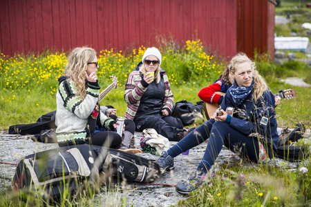 Traena, Norway - July 11 2015: group of young women friends sitting together and playing guitar on Sanna island, during Traenafestival music festival taking place on the small island of Traena and Sannaのeditorial素材