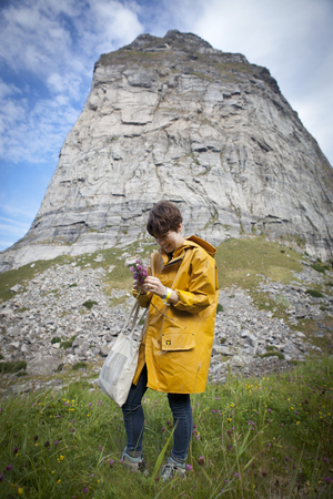 Traena, Norway - July 12 2014: during the Traenafestival, music festival taking place on the small island of Traena, young woman with a yellow rain coat pickingのeditorial素材
