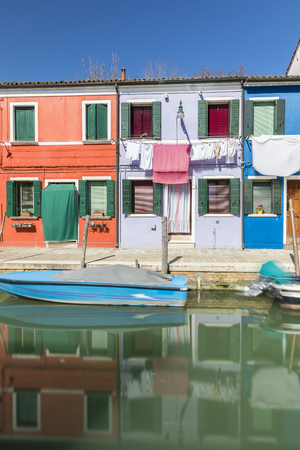 Typical canal and colorful facades with vibrant colors and laundry drying in famous fishermen village on the island of Burano, Venice, Italyの写真素材
