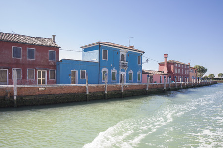 Colorful blue and pink houses on the quay of Mazzorbo Island near Burano in the Venice lagoon, viewed from the water, Italyの写真素材