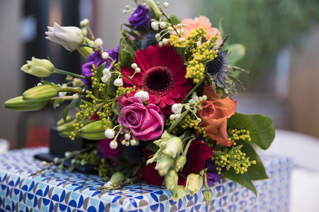 Bouquet of colorful flower lying on a wrapped giftの写真素材