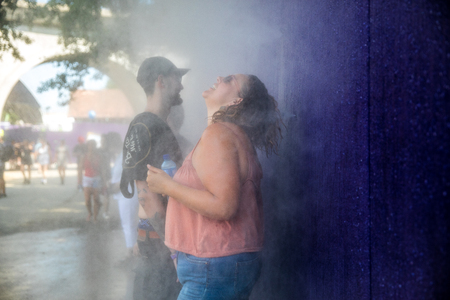 Nyon, Switzerland - 24 July 2019 : woman freshening up in the water mist of atomizer during a heat wave at paleo festivalのeditorial素材