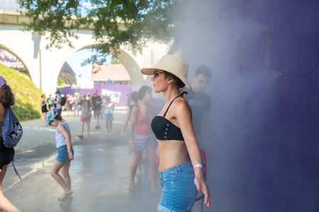 Nyon, Switzerland - 24 July 2019 : woman freshening up in the water mist of atomizer during a heat wave at paleo festivalのeditorial素材