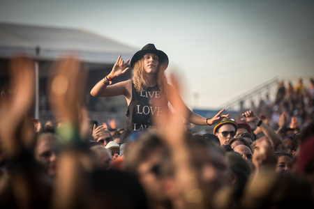 Nyon, Switzerland - 23 July 2019 : young lady up on a friend shoulder of girls in the audience crowed cheering during concert of Australian singer-songwriter and multi-instrumentalist Tash Sultana at Paleo Festival. On her t-shirt is written LOVE - LIVE -のeditorial素材
