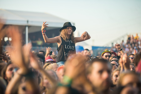 Nyon, Switzerland - 23 July 2019 : young lady up on a friend shoulder of girls in the audience crowed cheering during concert of Australian singer-songwriter and multi-instrumentalist Tash Sultana at Paleo Festival. On her t-shirt is written LOVE - LIVE -のeditorial素材