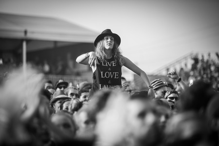 Nyon, Switzerland - 23 July 2019 : young lady up on a friend shoulder of girls in the audience crowed cheering during concert of Australian singer-songwriter and multi-instrumentalist Tash Sultana at Paleo Festival. On her t-shirt is written LOVE - LIVE -のeditorial素材