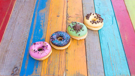 Colorful and tasty donuts on a colorful wood tableの写真素材