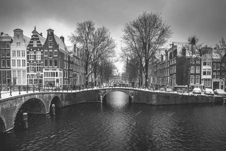 Winter snow view of Dutch canal and old houses in the historic city of Amsterdam, the Netherlands