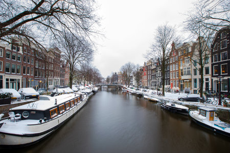 Winter snow view of Dutch canal and old houses in the historic city of Amsterdam, the Netherlandsの写真素材