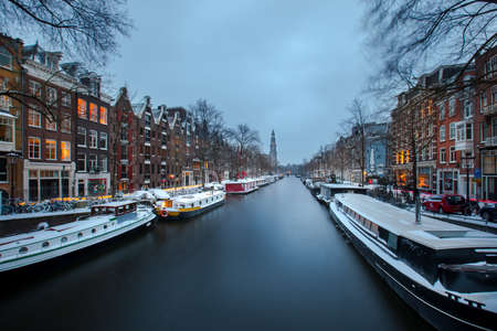 Winter snow view of Dutch canal and old houses in the historic city of Amsterdam during the blue hour, the Netherlandsの写真素材
