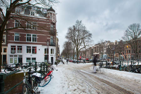 Winter snow view of Dutch canal and old houses in the historic city of Amsterdam, the Netherlandsの写真素材