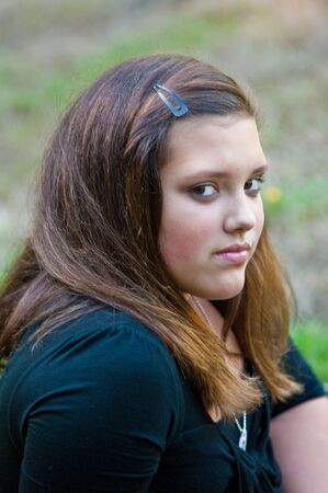A teenage girl sitting on grass showing three quarter viewの写真素材