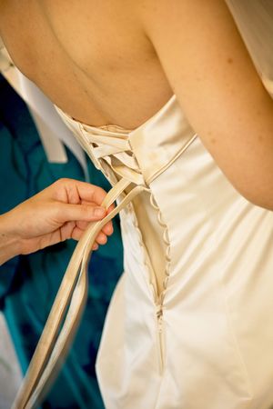 A hand is tying the knots on a bride's gownの写真素材