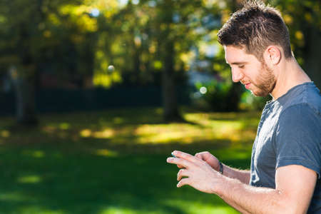Young man in park with smart phoneの写真素材