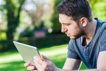 Young man in park with tabletの写真素材