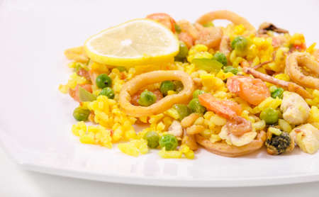 Paella with chicken and seafood on a white plate, close-up, side viewの写真素材