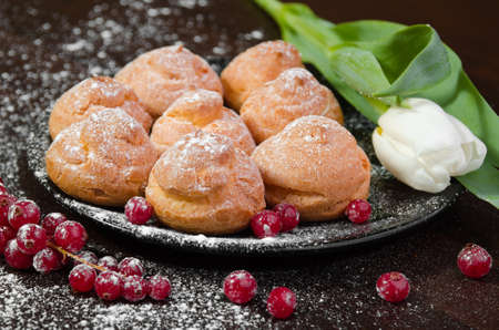 Profiteroles with cream on black plate, dark background, close-upの写真素材