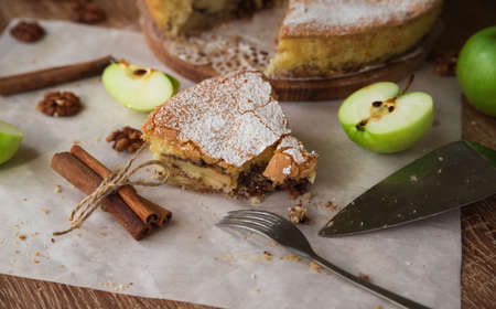Piece of apple pie with cinnamon and walnuts on a wooden table, close-upの写真素材