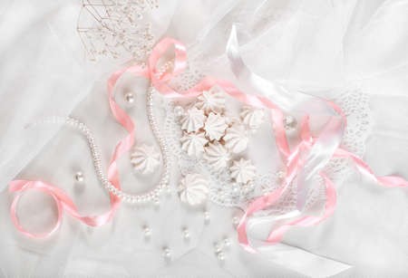 French meringue cookies for wedding background with pearls, pink and white satin ribbons and lace, flat lay, top viewの写真素材