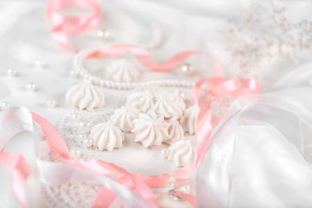 French meringue cookies for wedding background with pearls, pink and white satin ribbons and lace, close-upの写真素材