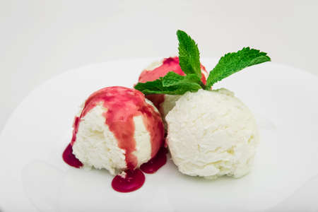 Three scoops of ice cream with strawberry syrup and mint on a white plate, white background, close-upの写真素材