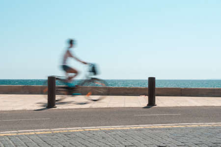 A girl riding a bicycle along the seaの写真素材
