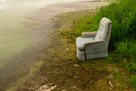 Old Recliner Sitting on Shore of Swampy Lakeの写真素材