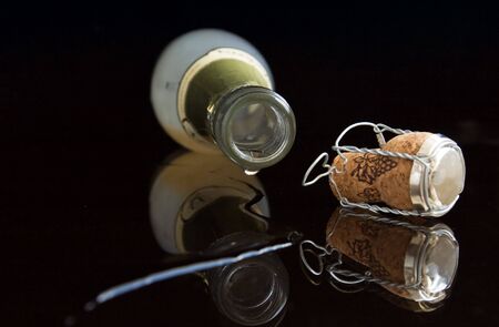 Opened wine bottle lays on a table. From her champagne flows
